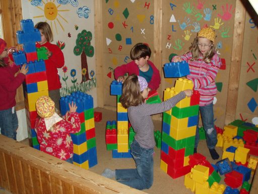 Kinder bauen mit bunten Bauklötzen in einem Spielzimmer.