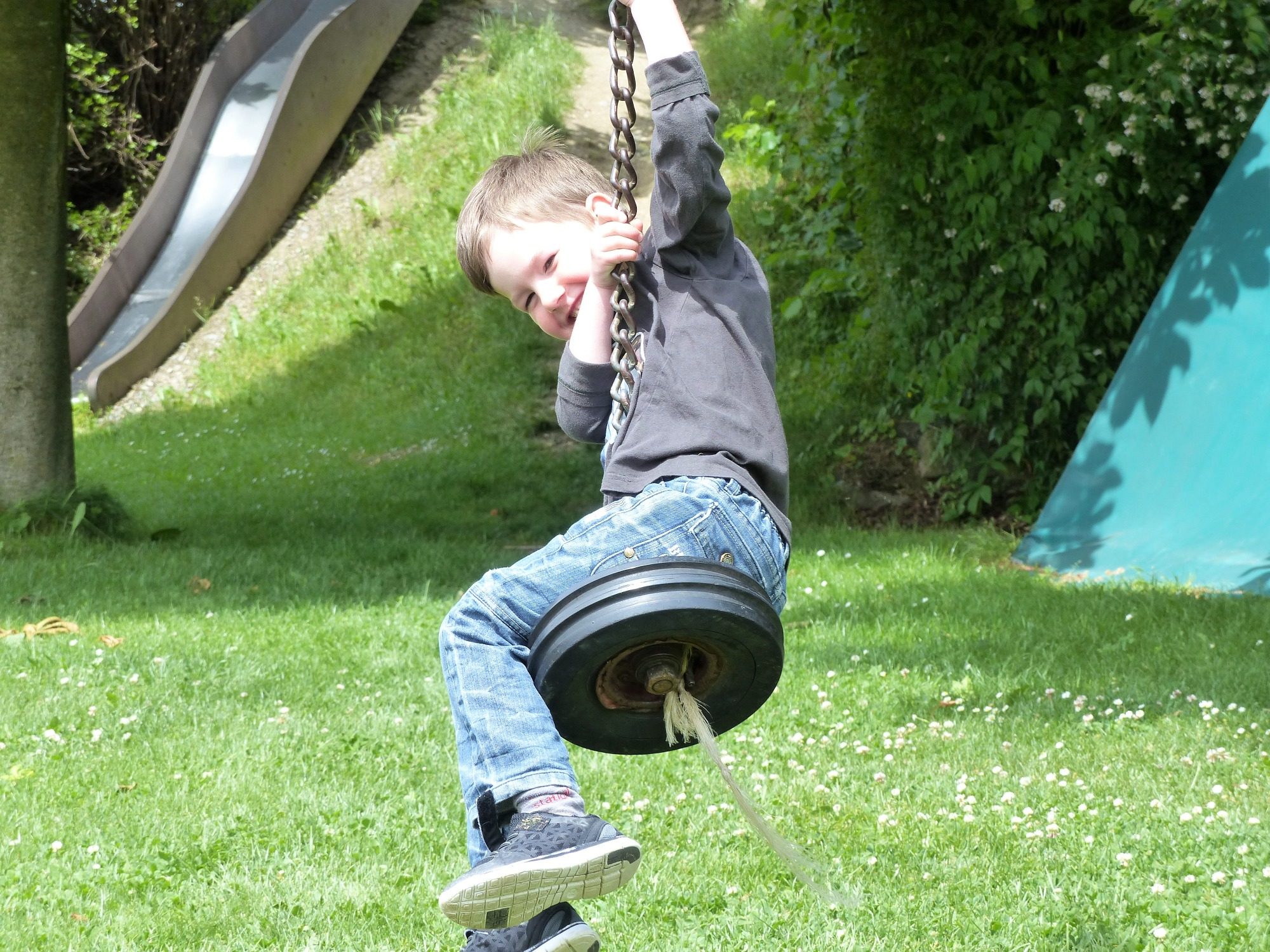 Ein Junge schwingt auf einer Reifen-Schaukel im Freien.