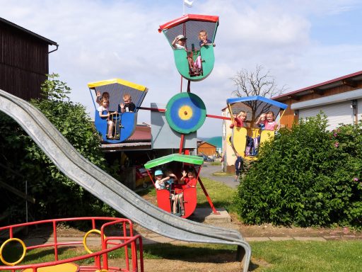 Bunte Kinderspielplatzanlage mit Rutschen und Kletterelementen, Kinder spielen und lachen.