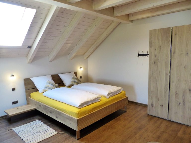 Gemütliches Schlafzimmer mit Doppelbett, Holzdekor und Dachfenster.